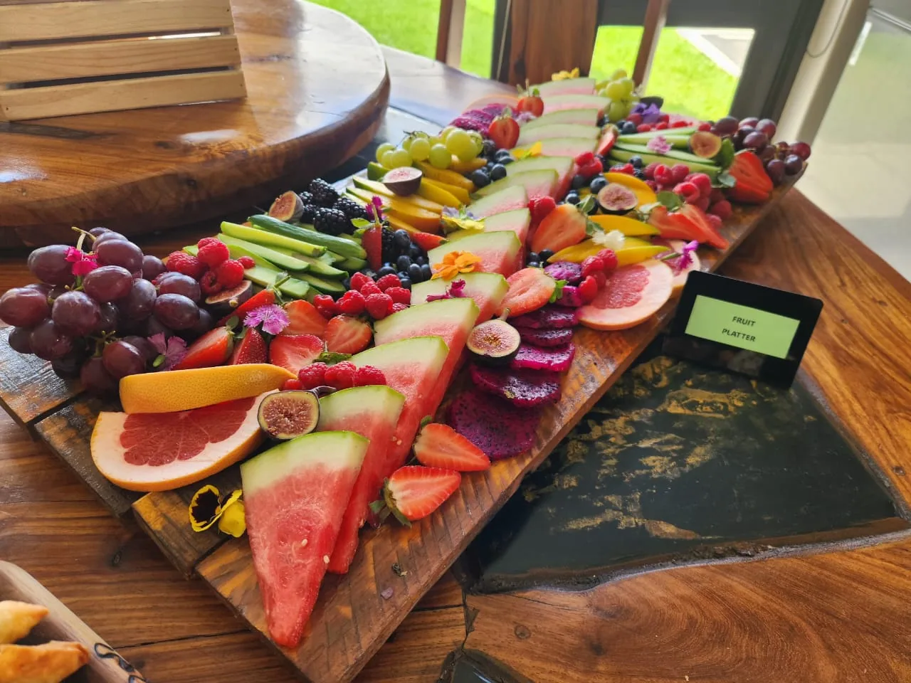 A long fruit platter with watermelon, figs, berries and grapes.