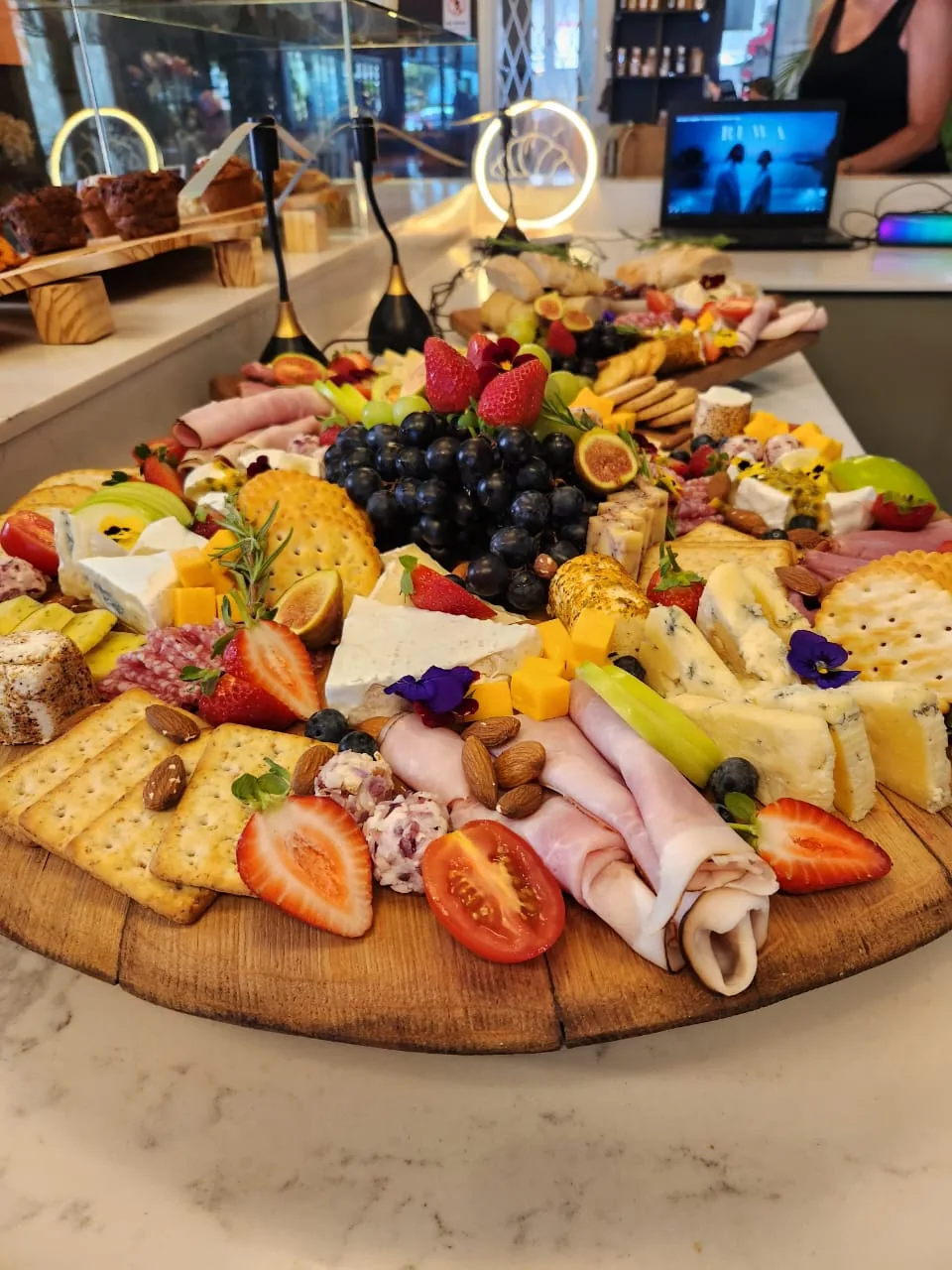 A round grazing platter of cold meats, cheeses, crackers and fruit.