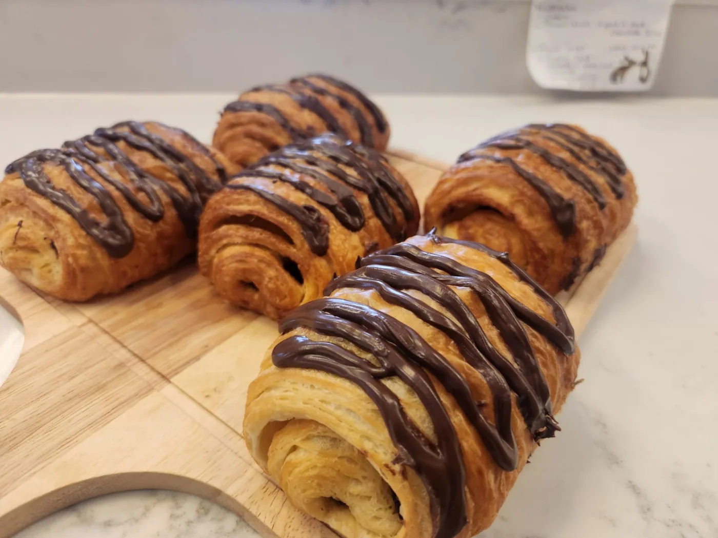 Freshly baked pain au chocolat drizzled with chocolate.