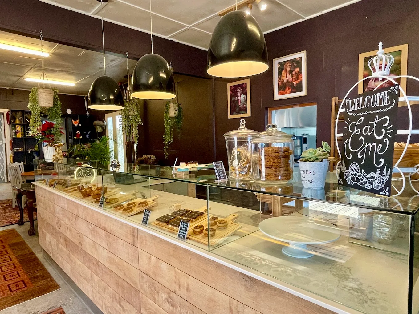 Inside On The Go — a timber bakery counter of pastries and tarts under warm pendant lights.